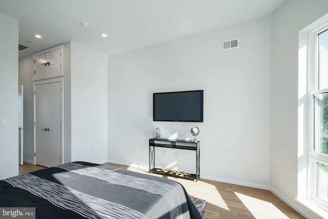 bedroom with light hardwood / wood-style floors and multiple windows