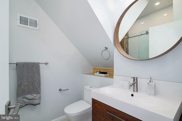 bathroom with toilet, vanity, vaulted ceiling, and a shower with door