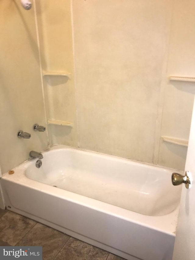 bathroom with tile patterned flooring and washtub / shower combination