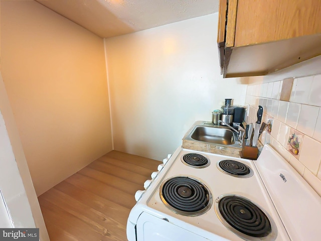 kitchen featuring white range, light hardwood / wood-style floors, tasteful backsplash, and sink