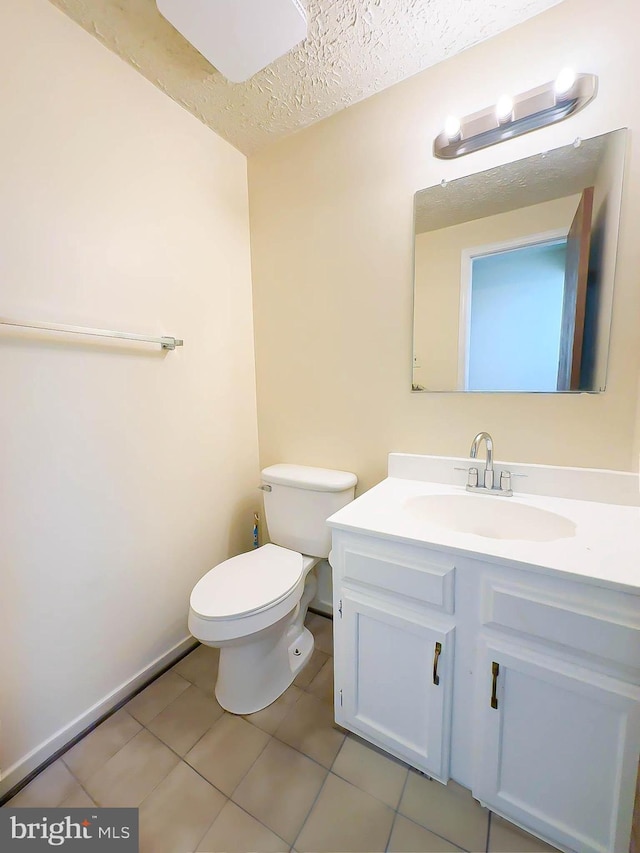 bathroom featuring tile patterned flooring, vanity, a textured ceiling, and toilet