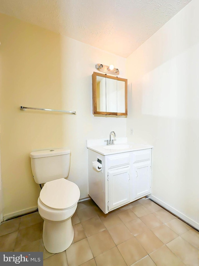 bathroom with tile patterned flooring, vanity, a textured ceiling, and toilet