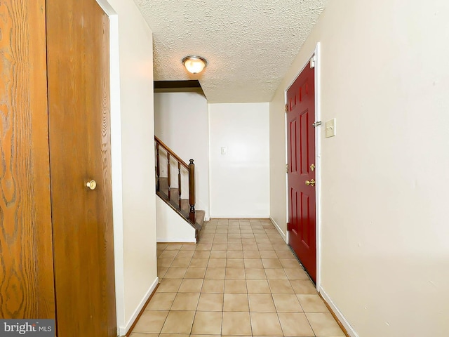 hallway with light tile patterned floors and a textured ceiling