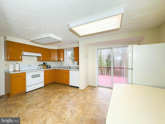 kitchen featuring a textured ceiling, white appliances, and sink