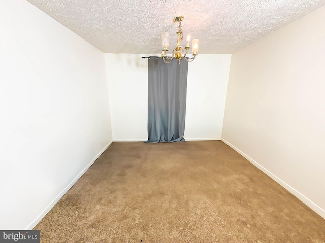 unfurnished room with carpet, a textured ceiling, and an inviting chandelier