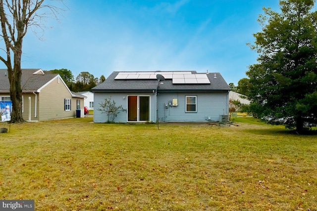 back of property featuring a lawn and solar panels