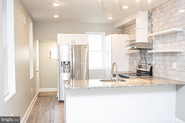 kitchen featuring sink, light stone countertops, appliances with stainless steel finishes, light hardwood / wood-style floors, and white cabinetry