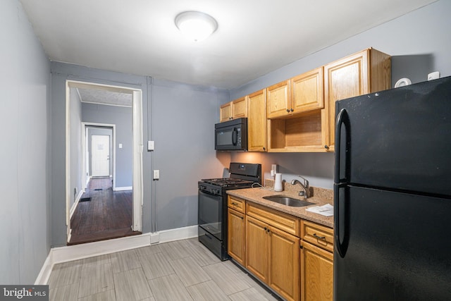 kitchen featuring light wood-type flooring, sink, light stone counters, and black appliances