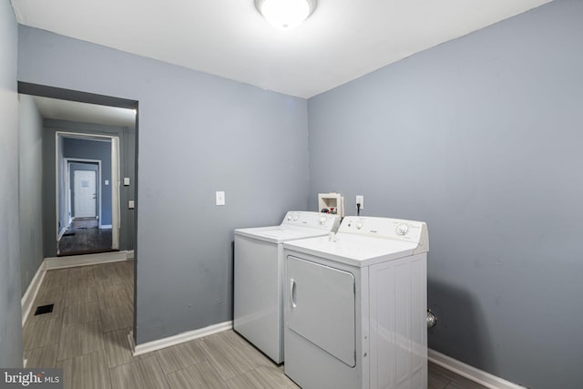 laundry room with washer and dryer and light wood-type flooring