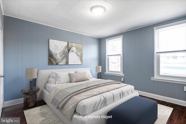 bedroom with dark hardwood / wood-style floors, multiple windows, and wood walls