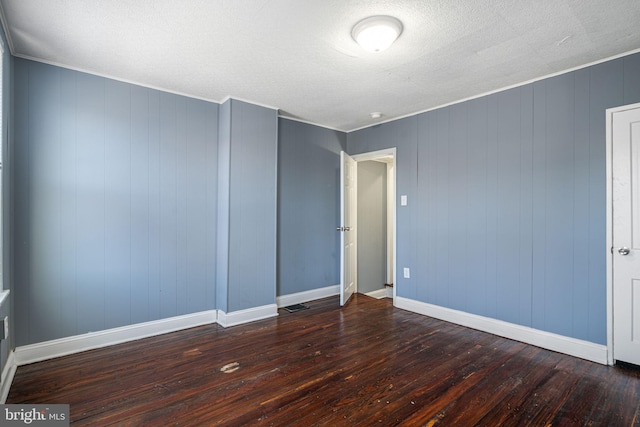 spare room featuring dark wood-type flooring and wooden walls