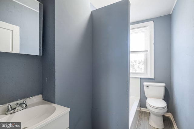 bathroom with hardwood / wood-style floors, vanity, toilet, and a bathing tub