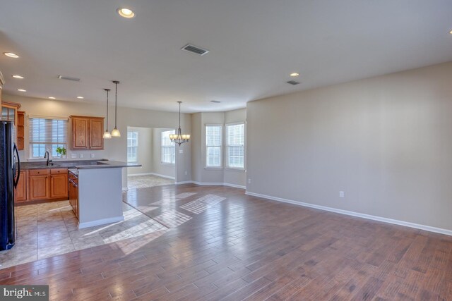 kitchen featuring black fridge, a center island, an inviting chandelier, and light hardwood / wood-style flooring