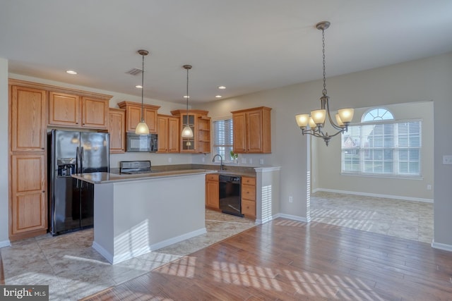 kitchen with a center island, black appliances, hanging light fixtures, light wood-type flooring, and a chandelier