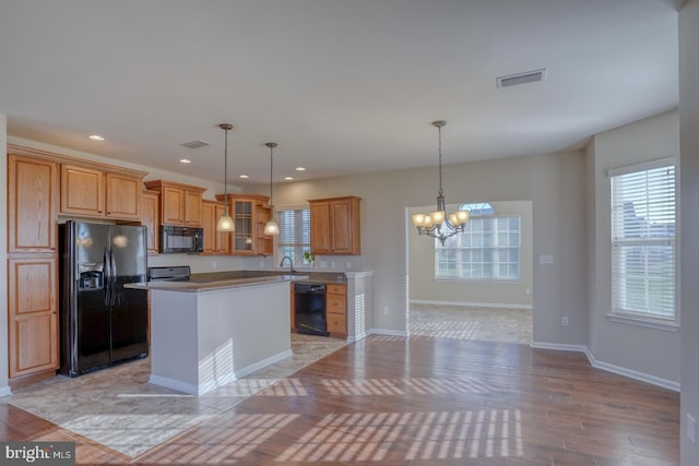 kitchen with a center island, black appliances, decorative light fixtures, and light hardwood / wood-style flooring