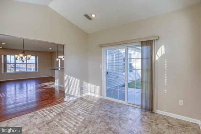 spare room with a chandelier, hardwood / wood-style floors, a wealth of natural light, and lofted ceiling