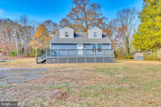 view of front facade with a wooden deck, a front lawn, and a shed