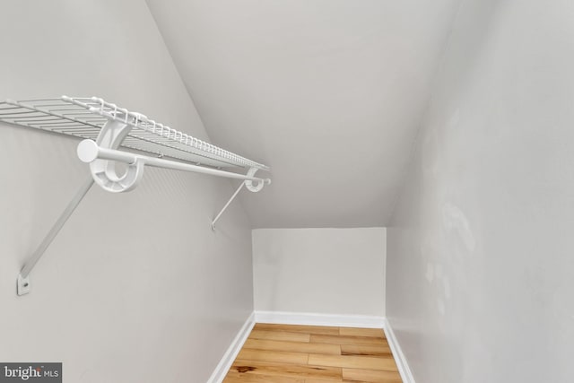 walk in closet with hardwood / wood-style floors and lofted ceiling