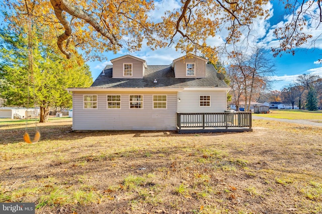 back of property featuring a deck and a lawn