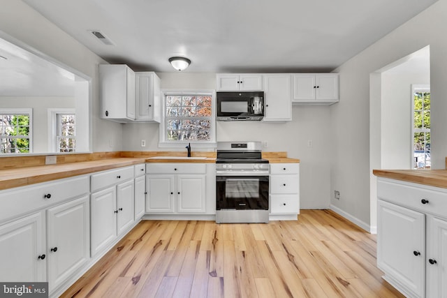 kitchen featuring butcher block countertops, white cabinets, and stainless steel range oven