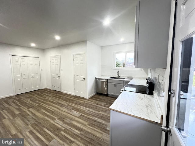 kitchen with dishwasher, sink, dark wood-type flooring, tasteful backsplash, and stove