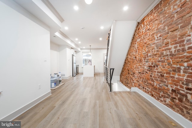 hall featuring brick wall and light wood-type flooring