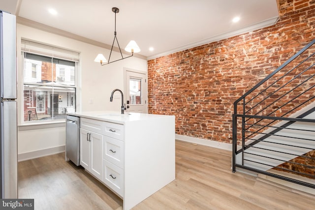 kitchen featuring a center island with sink, sink, ornamental molding, light hardwood / wood-style floors, and brick wall