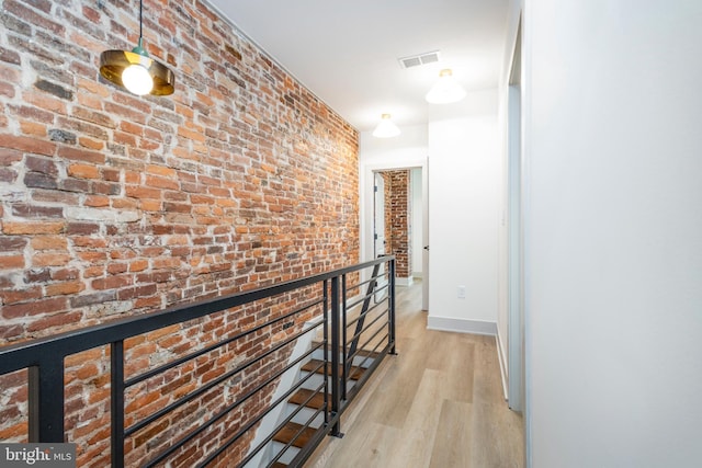 hall featuring light hardwood / wood-style flooring and brick wall