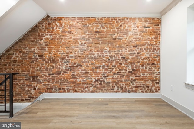 additional living space with wood-type flooring and brick wall