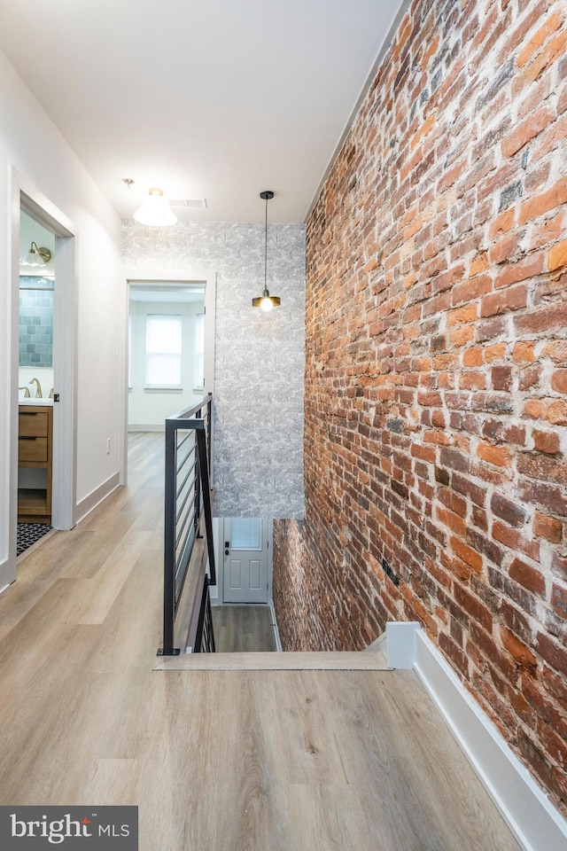 staircase featuring sink and brick wall