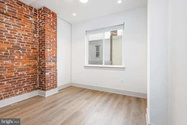 empty room featuring light hardwood / wood-style floors and brick wall