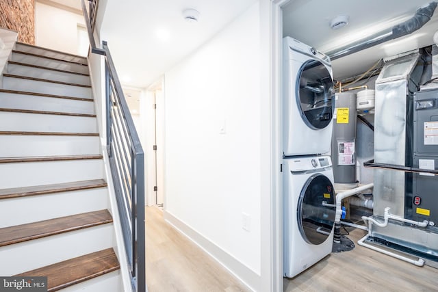 laundry area featuring electric water heater, light hardwood / wood-style floors, heating unit, and stacked washer / dryer