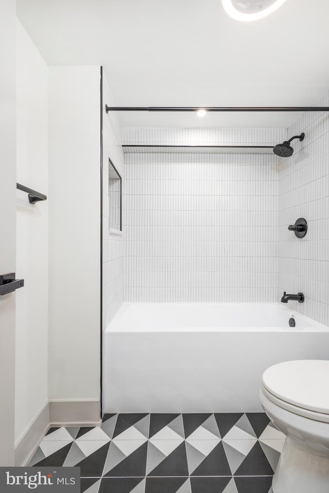 bathroom with tile patterned flooring, toilet, and tiled shower / bath