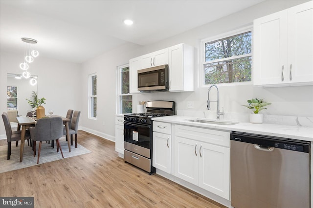 kitchen featuring light stone countertops, sink, light hardwood / wood-style floors, white cabinets, and appliances with stainless steel finishes