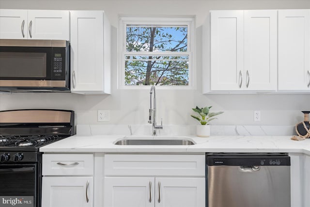 kitchen with white cabinets, sink, light stone countertops, and stainless steel appliances