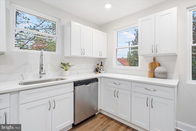 kitchen featuring white cabinets, light stone counters, sink, dishwasher, and light hardwood / wood-style floors