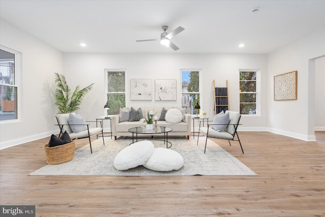 living room with light wood-type flooring, ceiling fan, and a healthy amount of sunlight