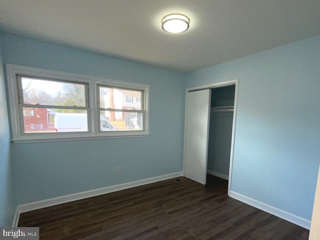 unfurnished bedroom featuring dark hardwood / wood-style flooring and a closet