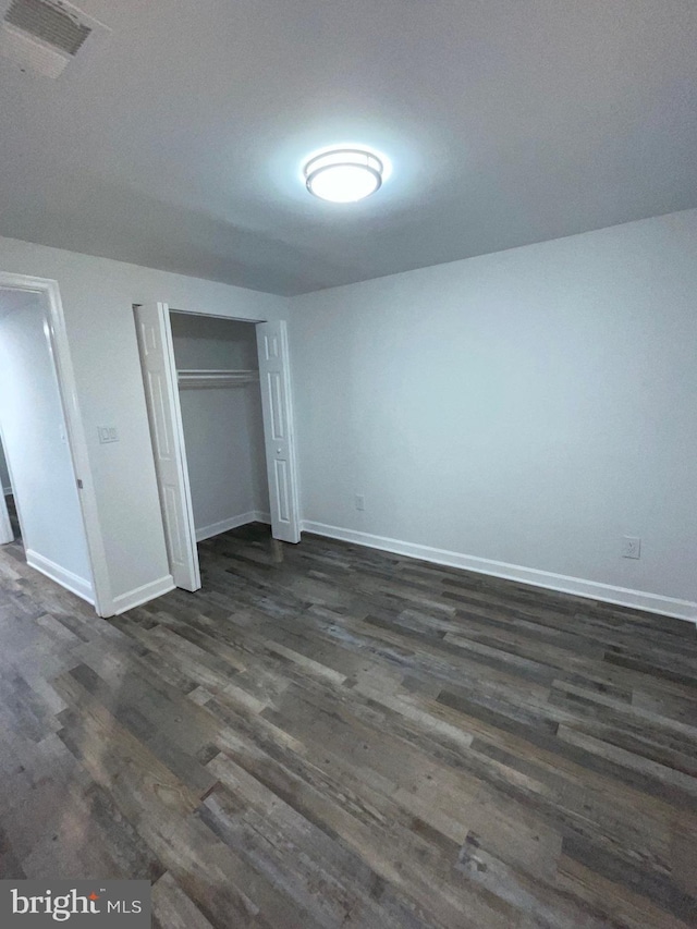 unfurnished bedroom with dark hardwood / wood-style flooring and a closet