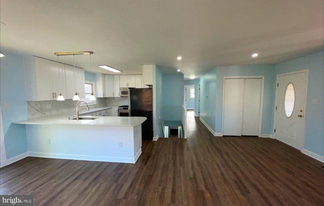 kitchen featuring kitchen peninsula, stainless steel appliances, sink, dark hardwood / wood-style floors, and white cabinetry