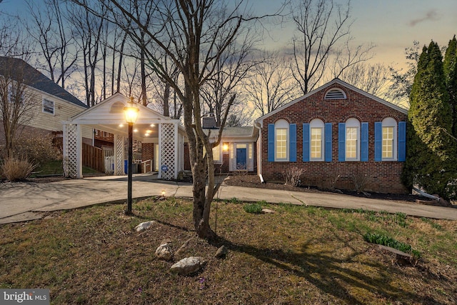 view of front of house featuring an attached carport, brick siding, and driveway