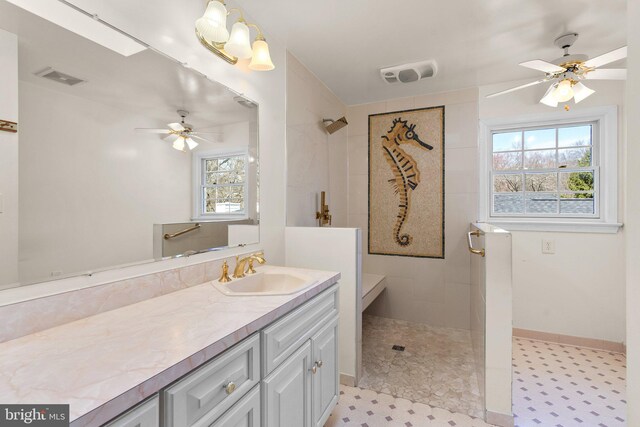 full bath with visible vents, tiled shower, a ceiling fan, and vanity