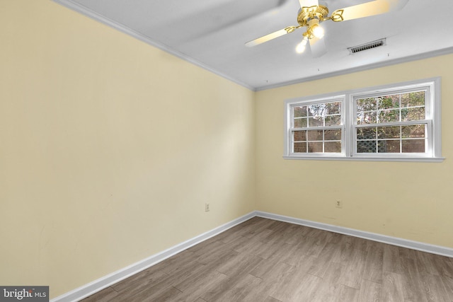 spare room with visible vents, ornamental molding, baseboards, and wood finished floors