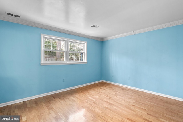 spare room with wood finished floors, visible vents, and baseboards