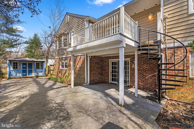 rear view of property with an outbuilding, stairway, a patio area, and brick siding