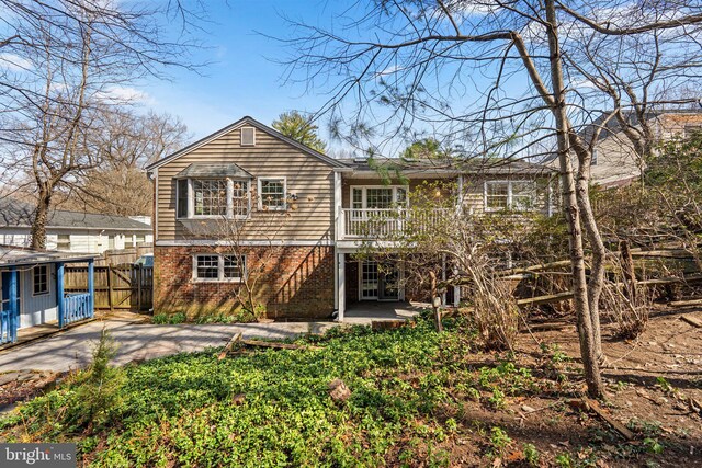 rear view of house with brick siding, fence, french doors, a patio area, and a gate