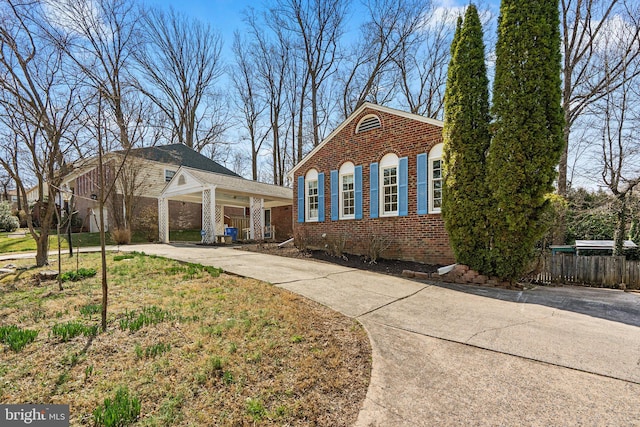 view of front of house with brick siding, driveway, and fence