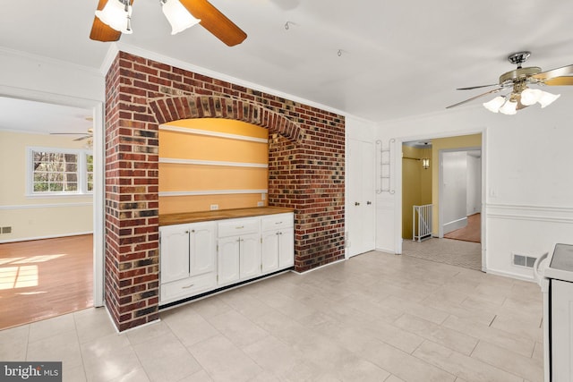 kitchen featuring a ceiling fan, crown molding, and white cabinetry