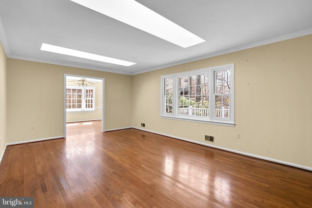 spare room featuring visible vents, crown molding, baseboards, a skylight, and wood-type flooring