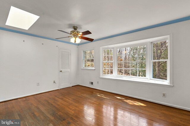 unfurnished room with visible vents, wood-type flooring, baseboards, and a skylight